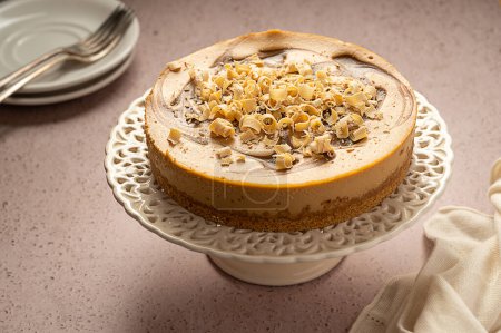 Photo for Whole caramel cheesecake on cake stand, neutral warm background. - Royalty Free Image