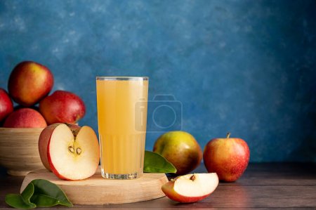 Apple cider cocktail, juice drink with fresh red apples, blue vibrant background.