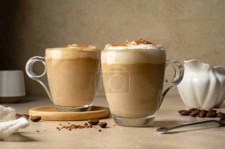 Deux tasses en verre avec boisson au café, latte avec mousse de lait et cannelle.