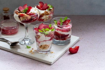 Trifles en couches de prunes rouges et de crème fouettée en dessert, verres en portions