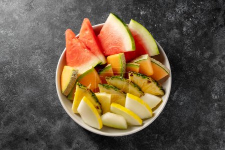 Foto de Bandeja de surtido de frutas, sandía, piña, melón y fresas. Fondo oscuro. - Imagen libre de derechos