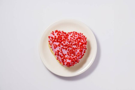 Téléchargez les photos : Donut en forme de coeur avec glaçure sur plaque blanche - en image libre de droit
