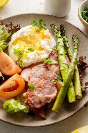Healthy breakfast - asparagus wrapped with bacon, benedict poached egg and salad