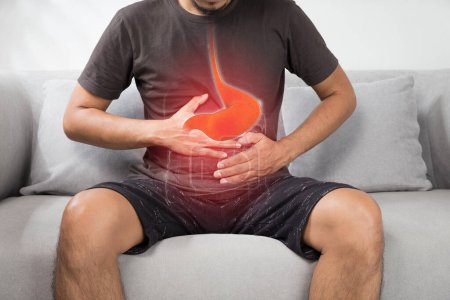 Reflujo ácido o acidez estomacal, la foto del estómago está en el cuerpo de los hombres contra el fondo gris, mala salud, anatomía masculina concep