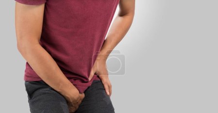 Photo for The man having groin pain on a gray background. Copy space on the right. - Royalty Free Image