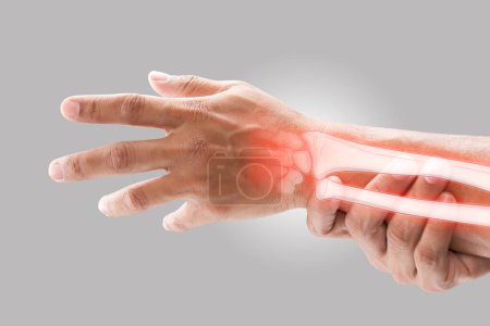 Photo for A man massaging painful wrist on a gray background. Pain concept. Osteoporosis - Royalty Free Image