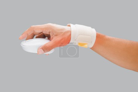 Téléchargez les photos : L'homme utilise un serre-poignet pour soutenir son poignet et prévenir la douleur lors de l'utilisation de la souris pendant le travail. - en image libre de droit