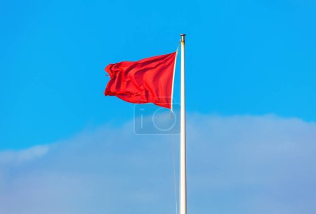 Téléchargez les photos : Drapeau rouge agitant contre le ciel bleu - en image libre de droit