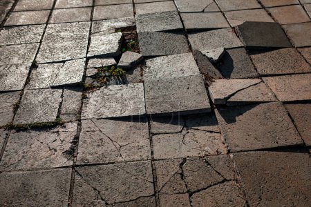 Shattered pavement . Broken cobblestones on the street