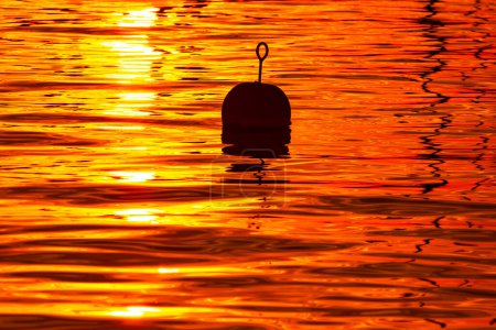 Foto de Silueta de flotador de pesca flotando en el mar al atardecer - Imagen libre de derechos