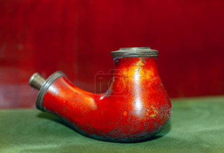 Photo for Old smoking pipe on a green tablecloth with a red background .  Pipe for smoke weathered by years of use - Royalty Free Image