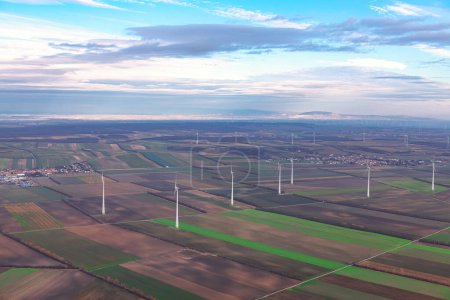 Photo for Wind farm and agricultural fields view from above. Wind turbines rotating harnessing the power of the wind to generate clean energy - Royalty Free Image