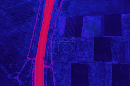 Agriculture fields with highway, colored in blue and red . Plowed lands seen from above