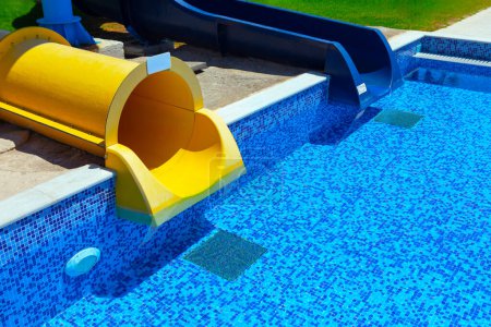 Swimming pool with blue water and yellow plastic slide 