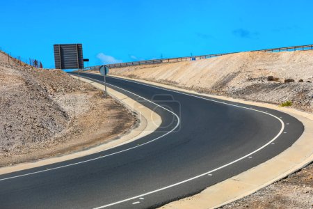 Curve of the road on the mountain with blue sky background. Asphalt Road in the Desert on a Sunny Day