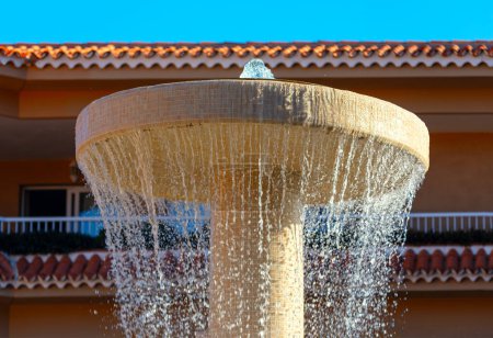 Wasserfontäne vor dem Haus mit blauem Himmel im Hintergrund. Spritzwasser im Sommer