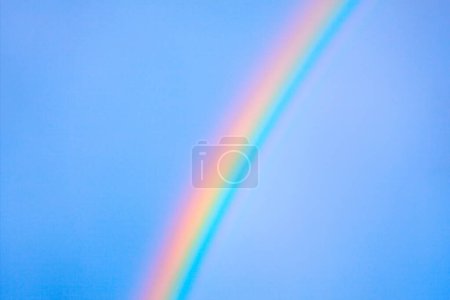 Foto de Arco iris vibrante a través del cielo azul brillante. Impresionante contraste de colores - Imagen libre de derechos