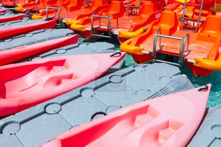 Fila de kayaks rojos de plástico en la playa. Barcos de ocio acuático 