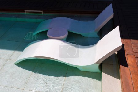 Swimming pool with sun loungers on the edge of the pool. Luxury resort swimming pool