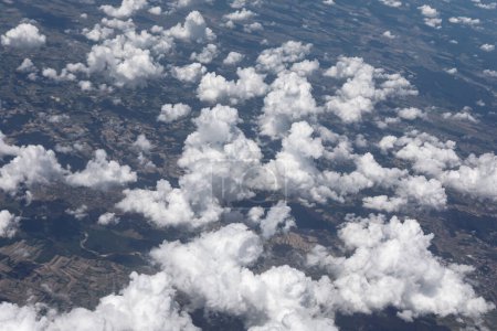 Aerial view of fluffy white clouds seen from the plane window. Airplane soaring through the sky