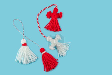 Photo for Traditional Martisor - symbol of holiday 1 March, Martenitsa, Baba Marta, beginning of spring and seasons changing in Romania, Bulgaria, Moldova. Greeting and post card for holidays. Blue background. - Royalty Free Image