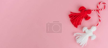 Traditional Martisor - symbol of holiday 1 March, Martenitsa, Baba Marta, beginning of spring and seasons changing in Romania, Bulgaria, Moldova. Greeting and post card for holidays. Pink background. Banner