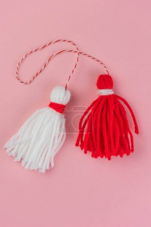Foto de Traditional Martisor - symbol of holiday 1 March, Martenitsa, Baba Marta, beginning of spring and seasons changing in Romania, Bulgaria, Moldova. Greeting and post card for holidays. Pink background. - Imagen libre de derechos
