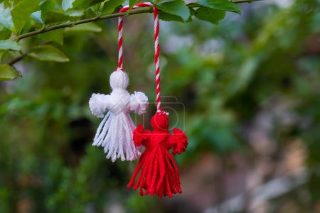 Photo for Traditional Martisor on green tree branch - symbol of 1 March, Martenitsa, Baba Marta, beginning of spring and seasons changing in Romania, Bulgaria, Moldova. Greeting and post card for holidays. - Royalty Free Image
