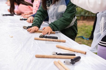 Photo for Kids cooking, roll out the dough and making matzah for Jewish holiday Passover Pesach at culinary master class for children outdoor in park. - Royalty Free Image