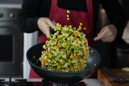 Téléchargez les photos : Chef cuisinier rôtit les légumes avec des fruits de mer dans wok casserole sur cuisinière à gaz. Légumes volants lévitation alimentaire en mouvement, habilement jeté par la main du chef. Expertise culinaire créative aéroportée. - en image libre de droit