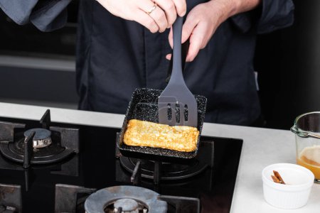 Foto de Chef man hands cooking Tamagoyaki or Tamago traditional Japanese Rolled Omelette receta, verter aceite y salsa en la sartén, para tortilla rectangular. - Imagen libre de derechos