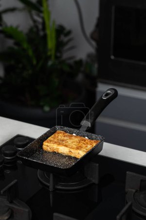 Foto de Chef man hands cooking Tamagoyaki or Tamago traditional Japanese Rolled Omelette recipe, made by rolling several layers of cooked scrambled whisking eggs in pan into a rectangular omelet. - Imagen libre de derechos