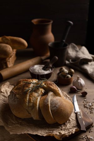 Photo for Homemade bread with parchment paper on wood table. Bread at wooden tabletop as baking concept - Royalty Free Image