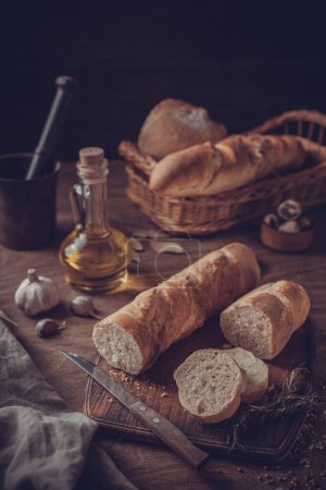 Photo for Sliced homemade bread at cutting board on wood table. Bread at wooden tabletop as baking concept - Royalty Free Image