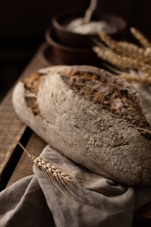 Photo for Homemade rye bread  and cloth napkin at wood table. Bakery concept still life and bread on wooden tabletop - Royalty Free Image