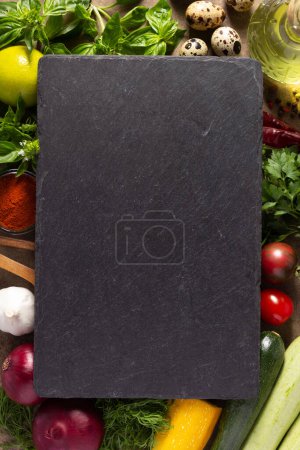 Photo for Variety of fresh vegetables and slate stone on table background. Cooking concept and salad ingredients at tabletop top view - Royalty Free Image