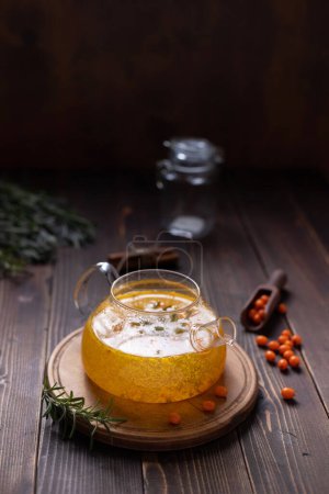 Photo for Teapot of sea buckthorn tea on a wooden table - Royalty Free Image