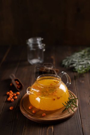 Photo for Teapot of sea buckthorn tea on a wooden table - Royalty Free Image