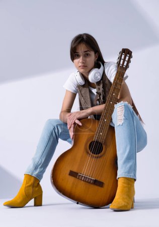 Photo for Young woman holdilng acoustic guitar. Musician sitting in studio with classic guitar - Royalty Free Image