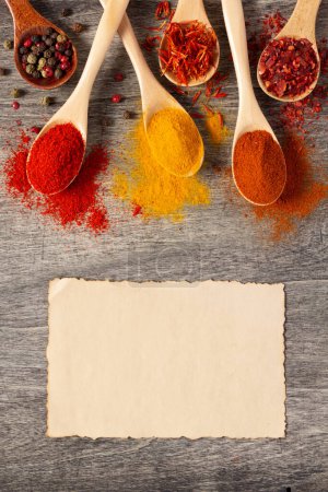 Photo for Variety of spices in spoon on table background with paper recipe. Cooking food ingredients at kitchen table top view - Royalty Free Image