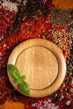 Photo for Wooden plate and variety of spices on table background. Food spice and ingredients at kitchen table closeup - Royalty Free Image
