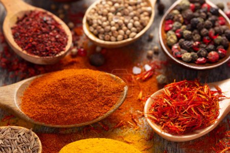 Photo for Paprika, pepper and turmeric spice in spoon on table background. Variety of spices and ingredients at kitchen table closeup - Royalty Free Image