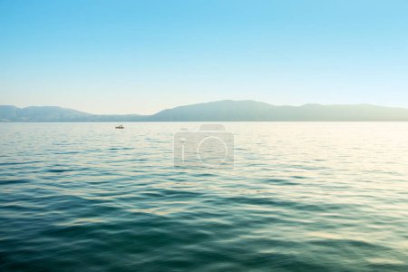 Seascape: sea with gentle waves and a distant shore under the blue sky
