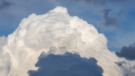 A dark blue cloud against a background of a large white cumulus cloud
