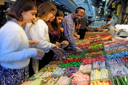 Téléchargez les photos : JERUSALEM - 11 NOV 2022 : Les Israéliens achètent des bonbons au marché Machaneh Yehudah à Jérusalem, en Israël. En Israël, la personne moyenne ne consomme que 14,5 grammes de sucre par jour. - en image libre de droit