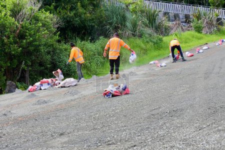 Téléchargez les photos : MANGONUI, NZL - FEB 02 2023:Small group of road workers emptying cement bags on broken road.Road construction workers usually earn between minimum wage and $24 an hour. - en image libre de droit