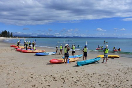 Photo for BYRON BAY, NSW - APR 02 2023: Large group of Australian people learn how to use kayak in Byron Bay beach. Kayak is a small, narrow human-powered watercraft that has been used for at least 4,000 years. - Royalty Free Image