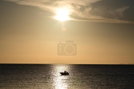Photo for Silhouette of unrecognizable fisherman in a fishing boat fishing during sunset in Torres Strait Island Queensland, Australia. - Royalty Free Image