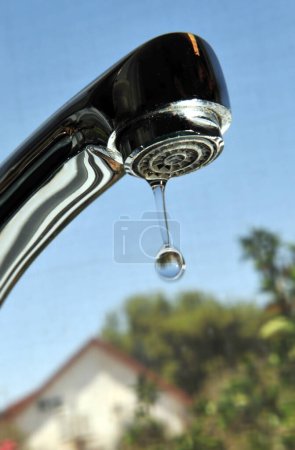 Leaky water tap in home kitchen. Concept photo of water waste.