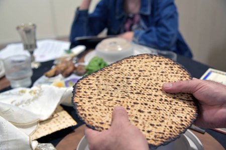 Jüdischer Mann hält handgemachtes Shmura Matzo ungesäuertes Fladenbrot in der Hand, das beim Pessach-Seder besonders für die Mitzwot des Essens von Matzo und Afikoman am Pessach-jüdischen Feiertag verwendet wird.